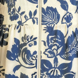 Blue floral V-neck smocked waist midi dress by Doe and Rae, shown on a model with flowing fabric and a stylish silhouette.
