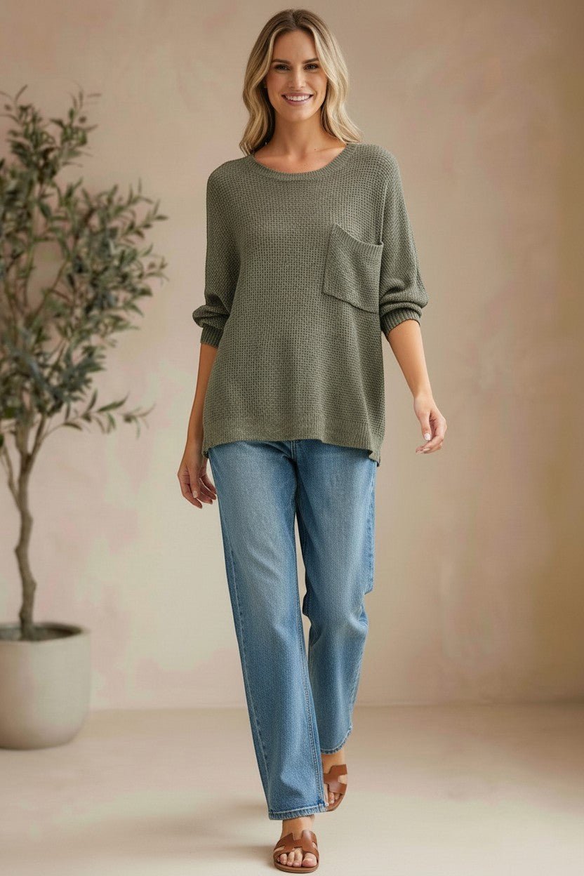 graced forest green dolman long sleeve knit sweater with a chest pocket worn by a smiling woman with blue jeans