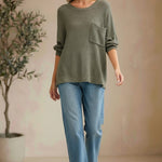 graced forest green dolman long sleeve knit sweater with a chest pocket worn by a smiling woman with blue jeans