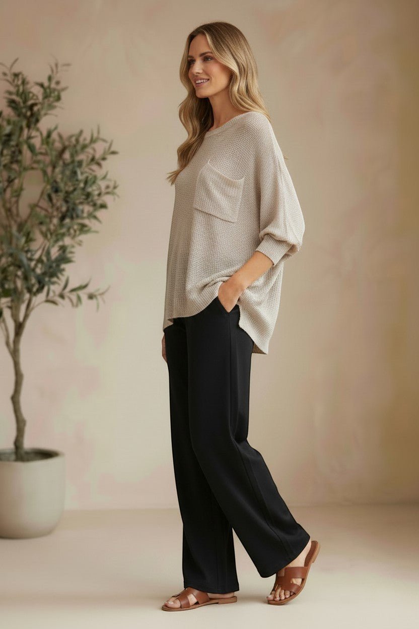 graced pebble dolman long sleeve knit sweater with pocket detail worn by a model with black trousers and sandals