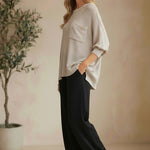 graced pebble dolman long sleeve knit sweater with pocket detail worn by a model with black trousers and sandals