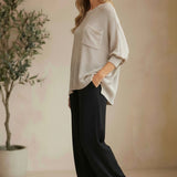 graced pebble dolman long sleeve knit sweater with pocket detail worn by a model with black trousers and sandals