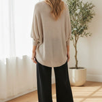 graced dolman long sleeve knit sweater in pebble beige worn by a woman with black wide-leg trousers