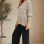 Model wearing a graced pebble dolman long sleeve knit sweater with a chest pocket and relaxed fit.