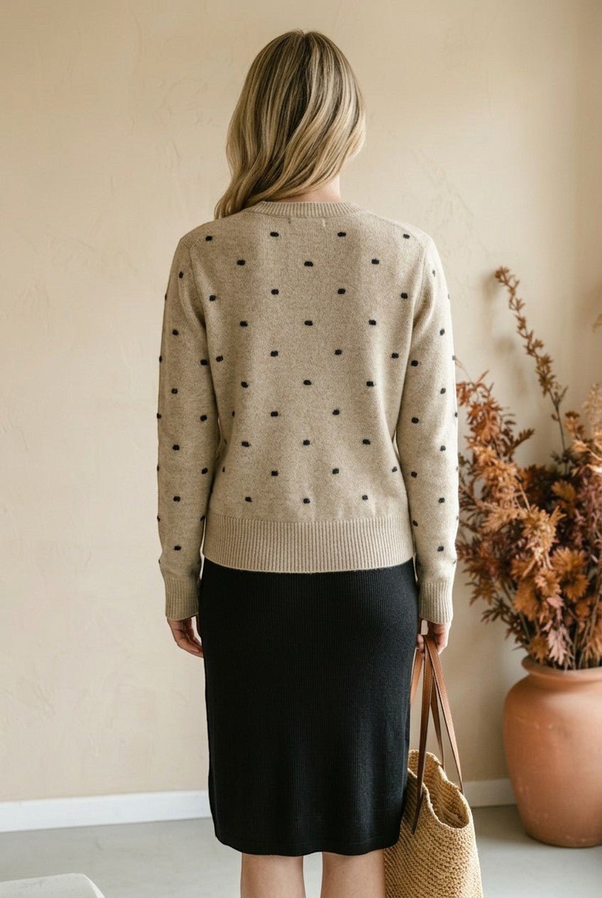 graced beige crewneck sweater with black polka dots worn by a woman with blonde hair from the back view