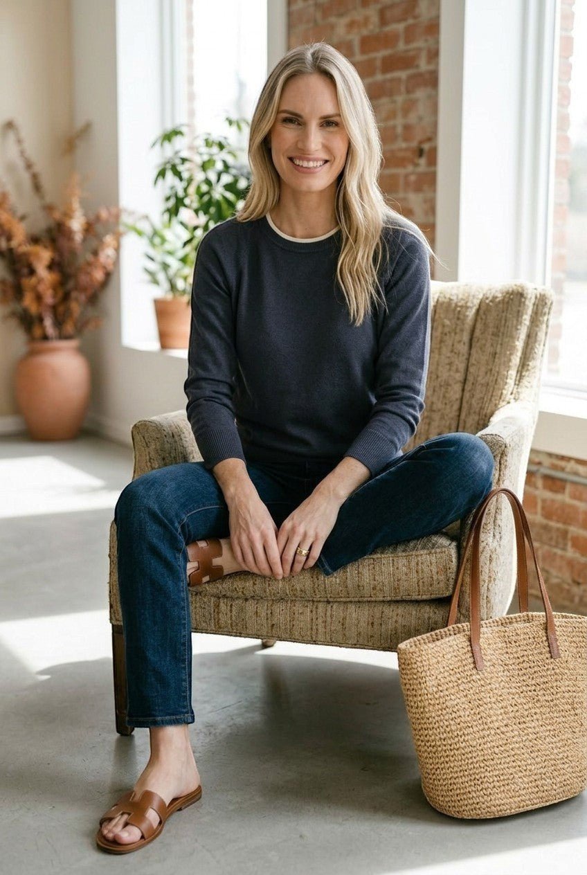 graced double layered sweater in charcoal with white neckline detail worn by a smiling woman in a cozy room