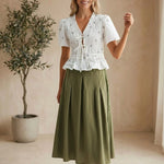 White embroidered peplum blouse by Camellia featuring pleated details, long sleeves, and intricate floral embroidery.