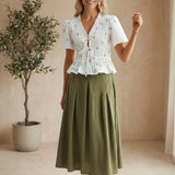 White embroidered peplum blouse by Camellia featuring pleated details, long sleeves, and intricate floral embroidery.