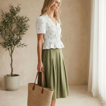 Camellia embroidered peplum blouse with pleated design, featuring intricate embroidery and a stylish, feminine silhouette.