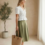Camellia embroidered peplum blouse with pleated design, featuring intricate embroidery and a stylish, feminine silhouette.