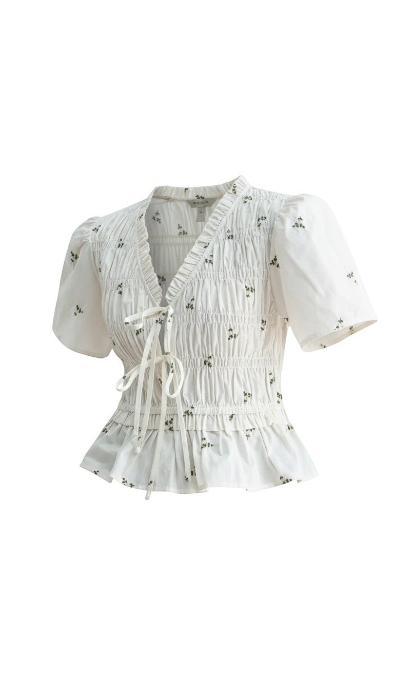 White embroidered peplum blouse from Camellia featuring pleated details and intricate embroidery, styled as a fashionable women's top.