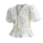 White embroidered peplum blouse from Camellia featuring pleated details and intricate embroidery, styled as a fashionable women's top.