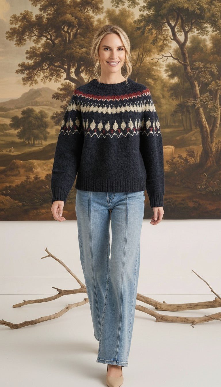 A woman wearing a graced navy blue Fair Isle crew neck sweater with a geometric pattern, paired with light wash jeans.