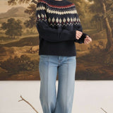 Woman wearing a navy graced Fair Isle crew neck sweater with geometric patterns, paired with light wash wide-leg jeans.