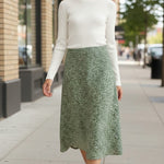 graced floral print midi skirt in green paired with a white ribbed top on a woman walking on a city sidewalk
