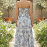 Blue and white floral smocked strapless midi dress by By Together, featuring a fitted bodice and flowing cotton-rayon fabric.