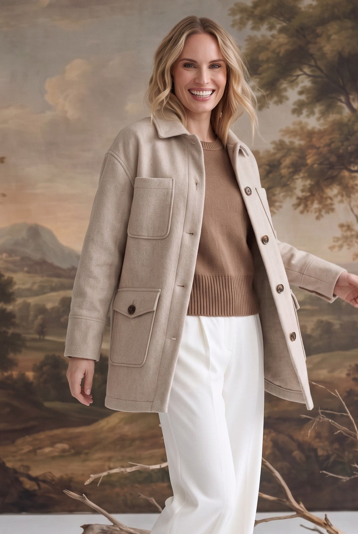 A woman wearing a beige graced Anna Five Button Coat over a brown sweater and white trousers in a studio setting.