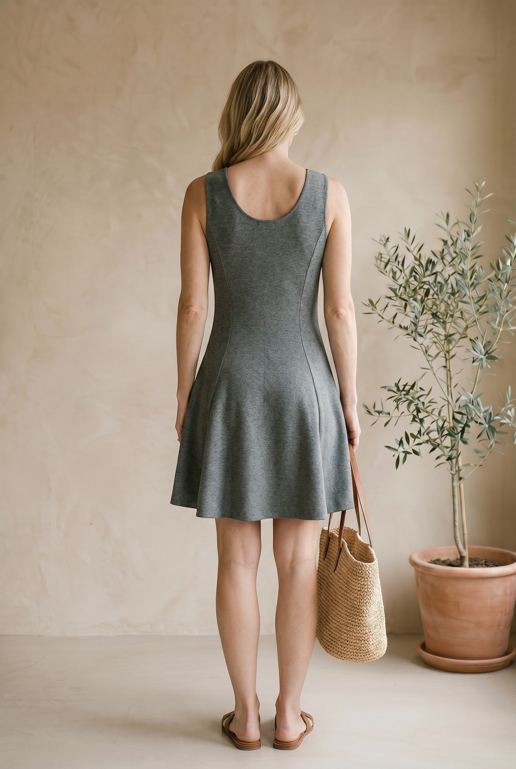 graced Anna Flare Dress in grey EcoViscose with a U-neckline and flared skirt, worn by a woman with a straw bag.