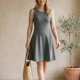 graced Anna Flare Dress in grey EcoViscose with U-neckline and tennis-inspired skirt worn by a smiling woman