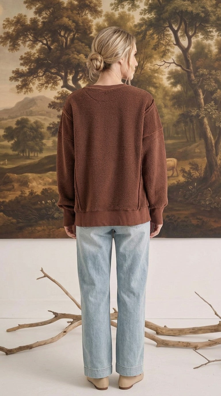 Back view of a woman wearing the graced Ashley oversized chocolate brown fleece top with light wash jeans