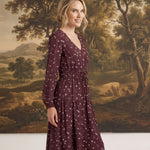 graced Audrey floral midi dress in burgundy with long sleeves, v-neckline, and a cinched waist on a model