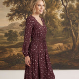 graced Audrey floral midi dress in burgundy with long sleeves, v-neckline, and a cinched waist on a model