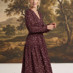 graced Audrey floral midi dress in burgundy with long sleeves, v-neckline, and tiered skirt on a model