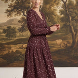 graced Audrey floral midi dress in burgundy with long sleeves, v-neckline, and tiered skirt on a model