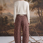 Back view of a model wearing graced chocolate-brown barrel pants with a spotted Bambi print and waist bow tie.