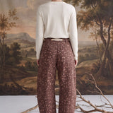 Back view of a model wearing graced chocolate-brown barrel pants with a spotted Bambi print and waist bow tie.