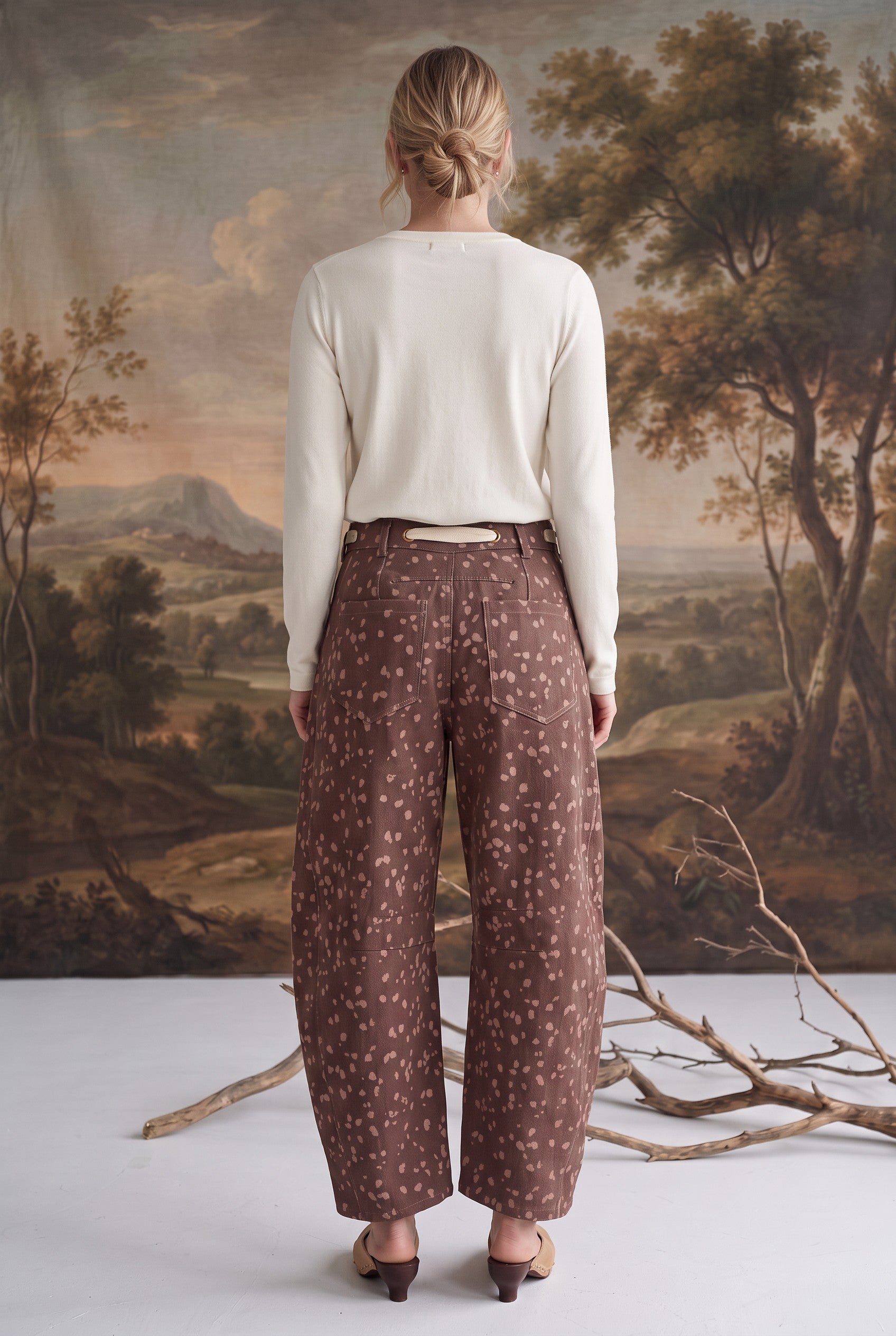 Back view of a model wearing graced chocolate-brown barrel pants with a spotted Bambi print and waist bow tie.
