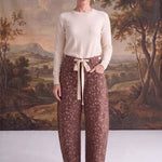 Model wearing graced chocolate-brown barrel pants with a spotted Bambi print, bow-tie waist, and seamed knee detail.