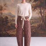Model wearing graced chocolate-brown barrel pants with a spotted Bambi print, bow-tie waist, and seamed knee detail.