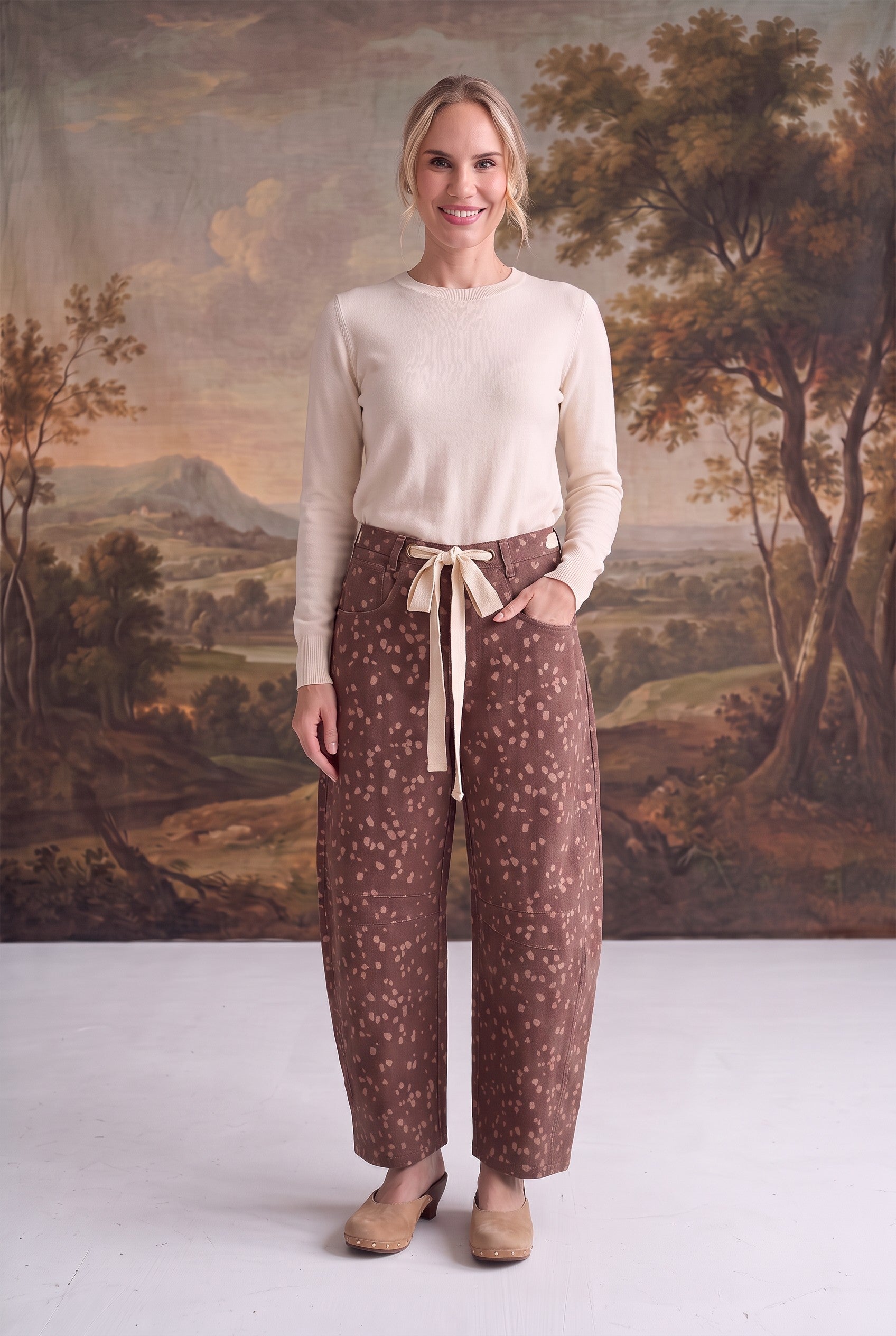 Model wearing graced chocolate-brown barrel pants with a spotted Bambi print, bow-tie waist, and seamed knee detail.