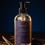 Clear hand soap bottle with black pump and 'graced Egg Harbor' label on a dark background