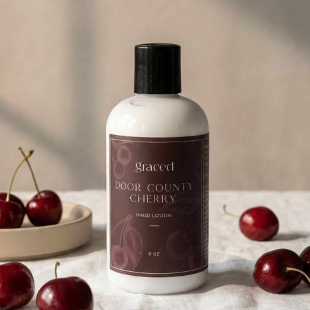 Bottle of Door County Cherry lotion with cherries on a neutral background