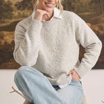Woman wearing a graced beige pullover sweater with delicate floral embroidery, layered over a white collared shirt.