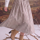 graced Beatrice plaid midi skirt with a smocked waist and button-down front, paired with tan ankle boots.