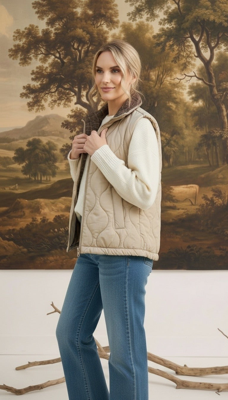 Model wearing a graced beige quilted vest with a plaid collar over a white sweater and blue jeans