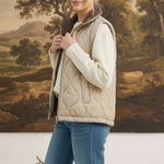 Model wearing a graced beige quilted vest with a plaid collar over a white sweater and blue jeans