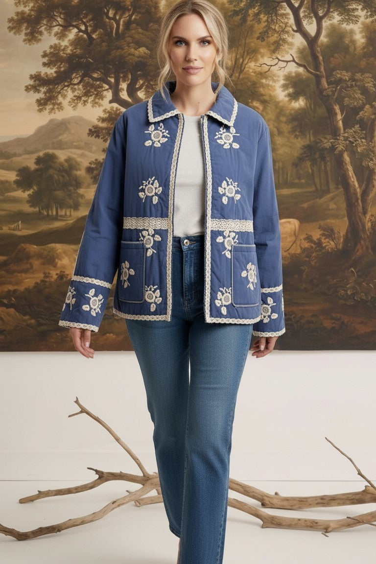 Model wearing a graced blue cotton jacket with white floral embroidery and lace trim over a white top and blue jeans.