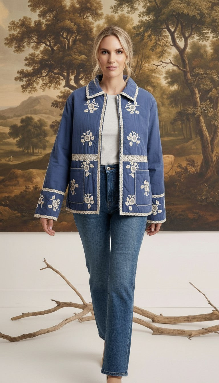 Model wearing a graced blue cotton jacket with white floral embroidery and lace trim over a white top and blue jeans.