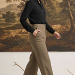 A woman wearing graced houndstooth knit straight pants in brown paired with a black blouse in a studio setting.