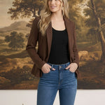 graced knit blazer jacket in brown worn over a black top and blue jeans by a blonde model in front of a landscape