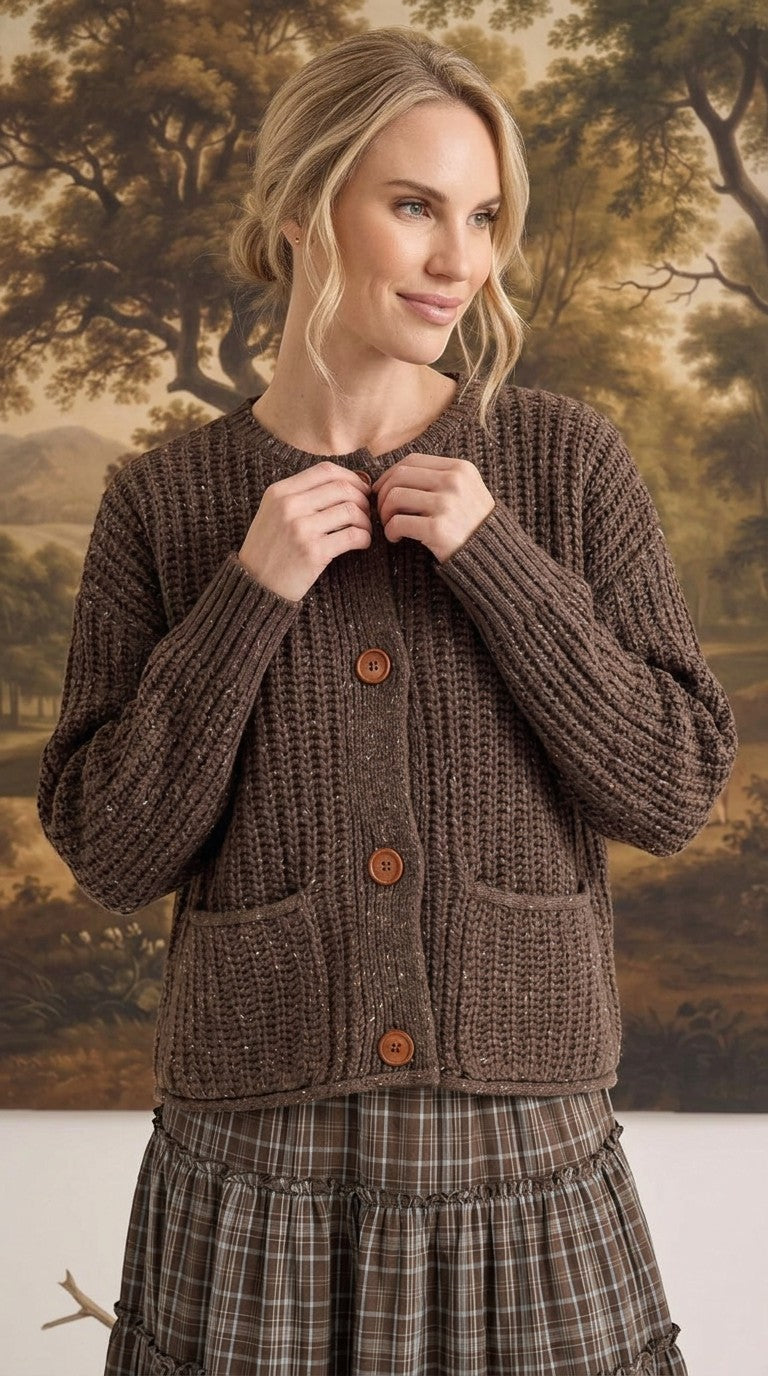 Model wearing a graced brown ribbed knit cardigan with raw edges, button front, and pockets over a plaid skirt