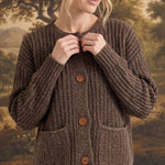 Model wearing a graced brown ribbed knit cardigan with raw edges, button front, and pockets over a plaid skirt