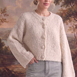 graced The Callie fuzzy knit cardigan in cream with a round neckline and button front, worn by a model.