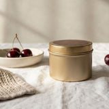 Graced Door County Cherry natural soy candle in a gold tin, showcasing a cozy home fragrance with cherry scent.
