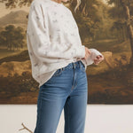 Model wearing graced The Courtney Horse Textured Top in cream with a subtle horse motif, paired with blue jeans.