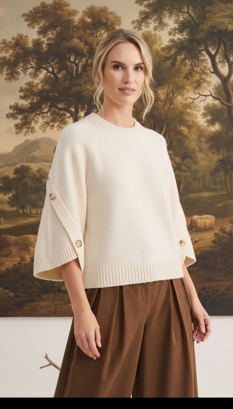 graced cream knit top with button-detailed sleeves worn by a model in a relaxed fit